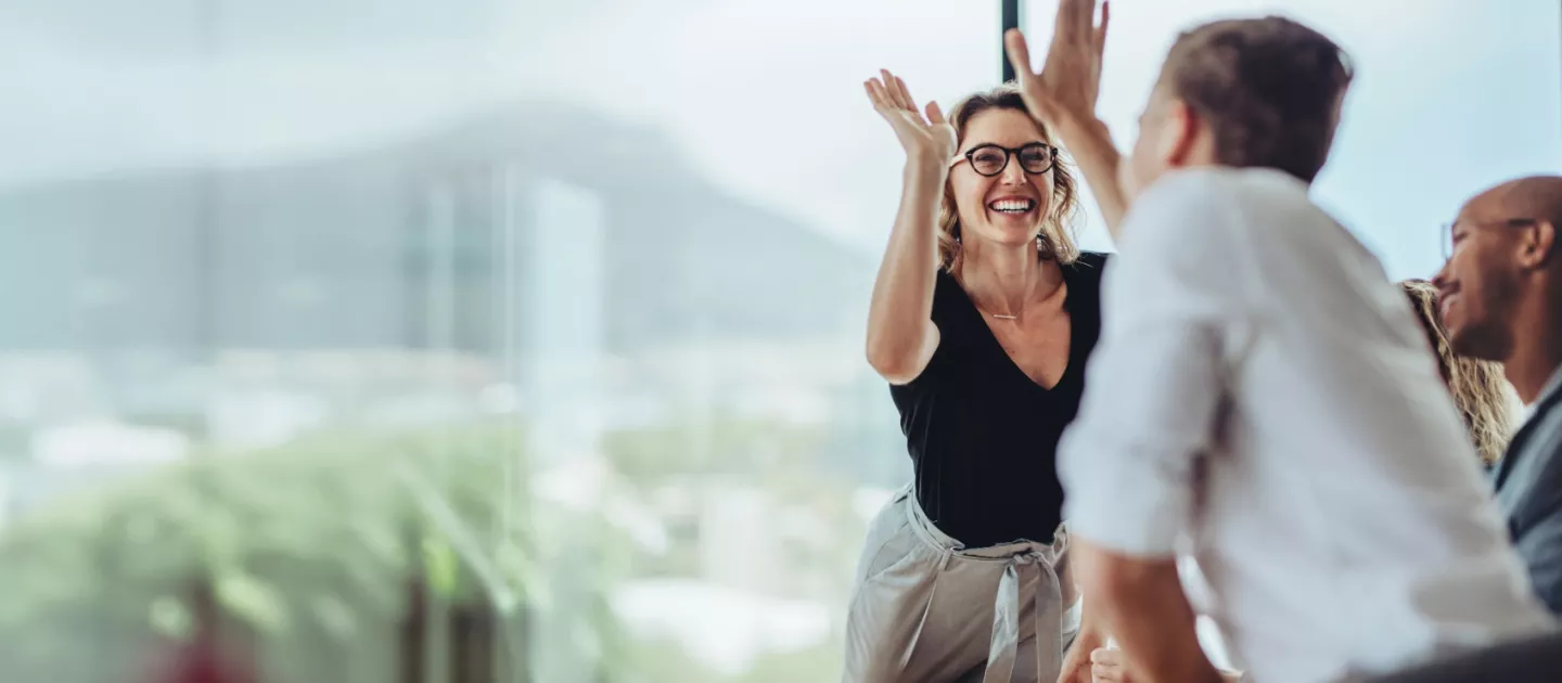 Office team working together high fiving across the table