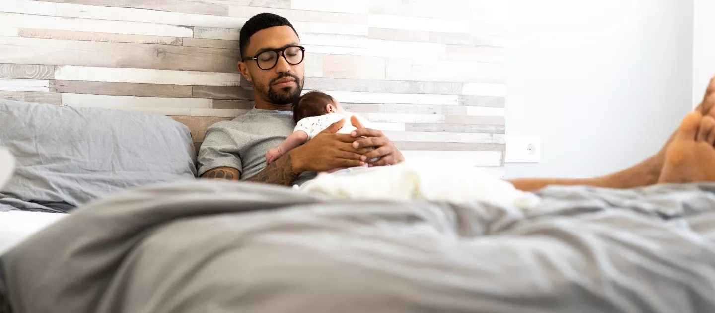 New father and newborn resting peacefully in bed