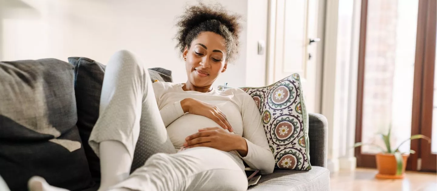 Mom relaxing on couch touching belly