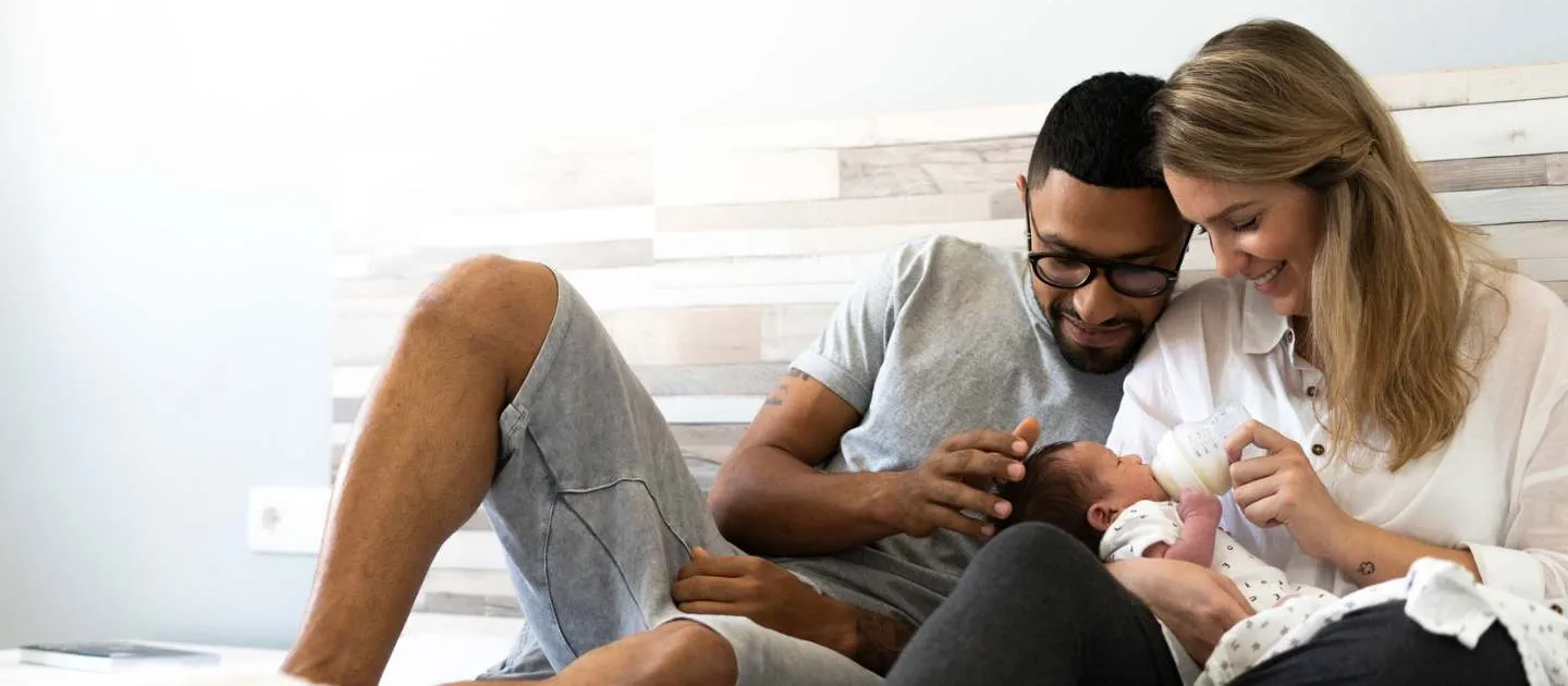 Happy parents feeding newborn