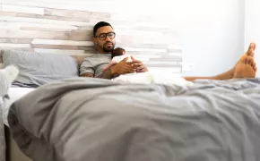 father-resting-with-newborn-in-bed