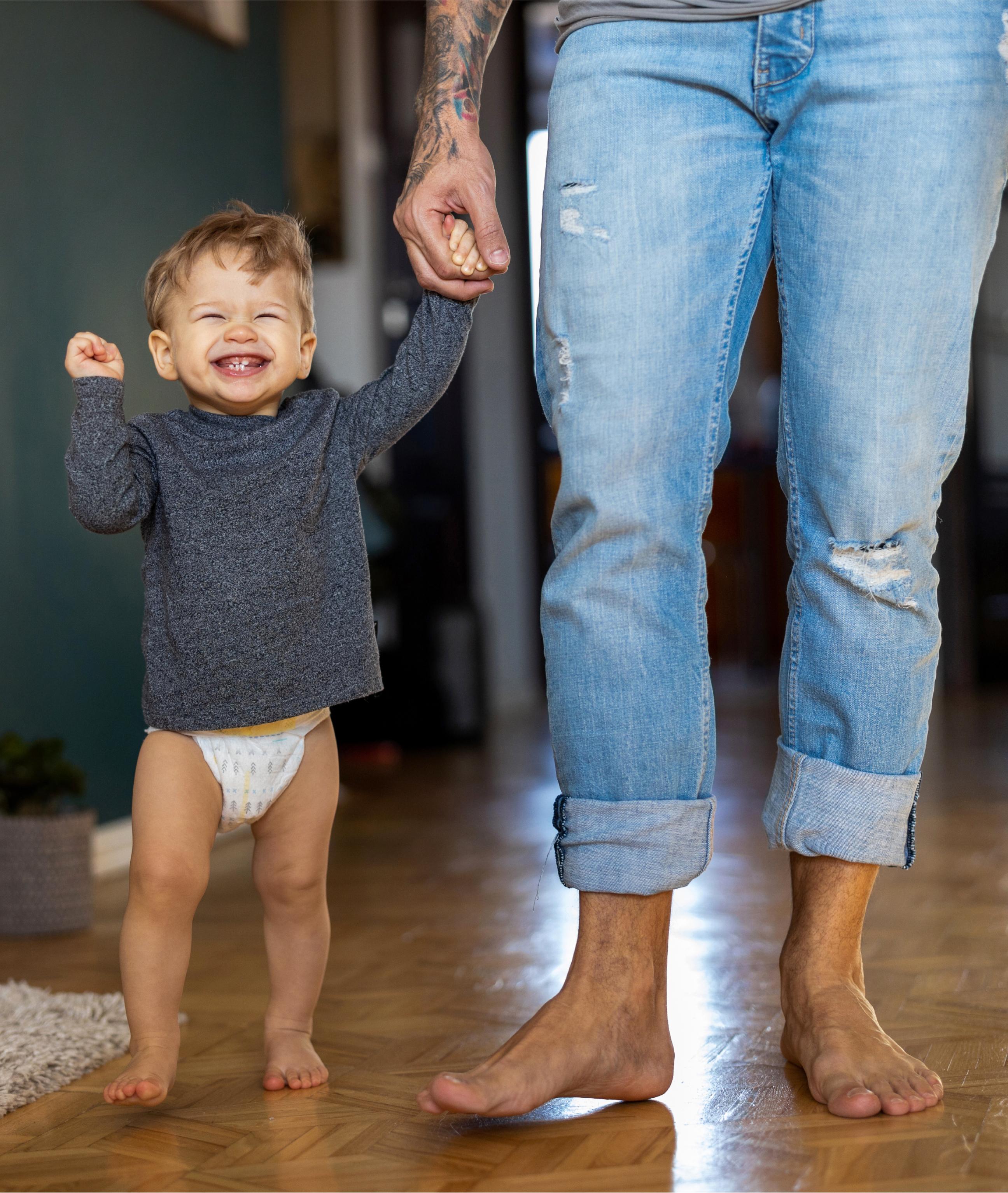 excited-toddler-holding-fathers-hand-living-room